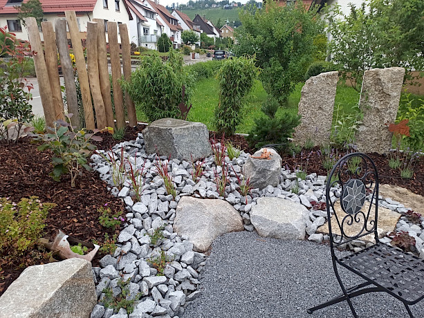 Steingarten mit Trennwand im Hintergrund und Metallstuhl